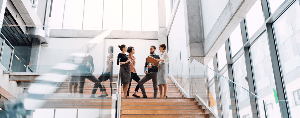 A group of young businesspeople standing on a staircase, talking.